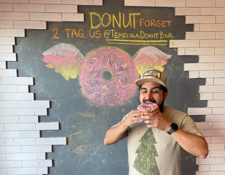 Man eating a donut in front of brick wall